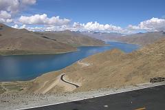 Tibet 05 01 Yamdrok Tso Kamba La The road from Lhasa to Gyantse (260km) took us over two mountain passes. From the Kamba La (4794m), we had a fantastic view of the beautiful Yamdrok Tso (Turquoise lake) with Nojin Kangtsang (7191m) behind, hidden in the clouds. In the foreground is the new paved road just opened in June 2005, in preparation for the 40th anniversary of the creation of the Tibet Autonomous Region.